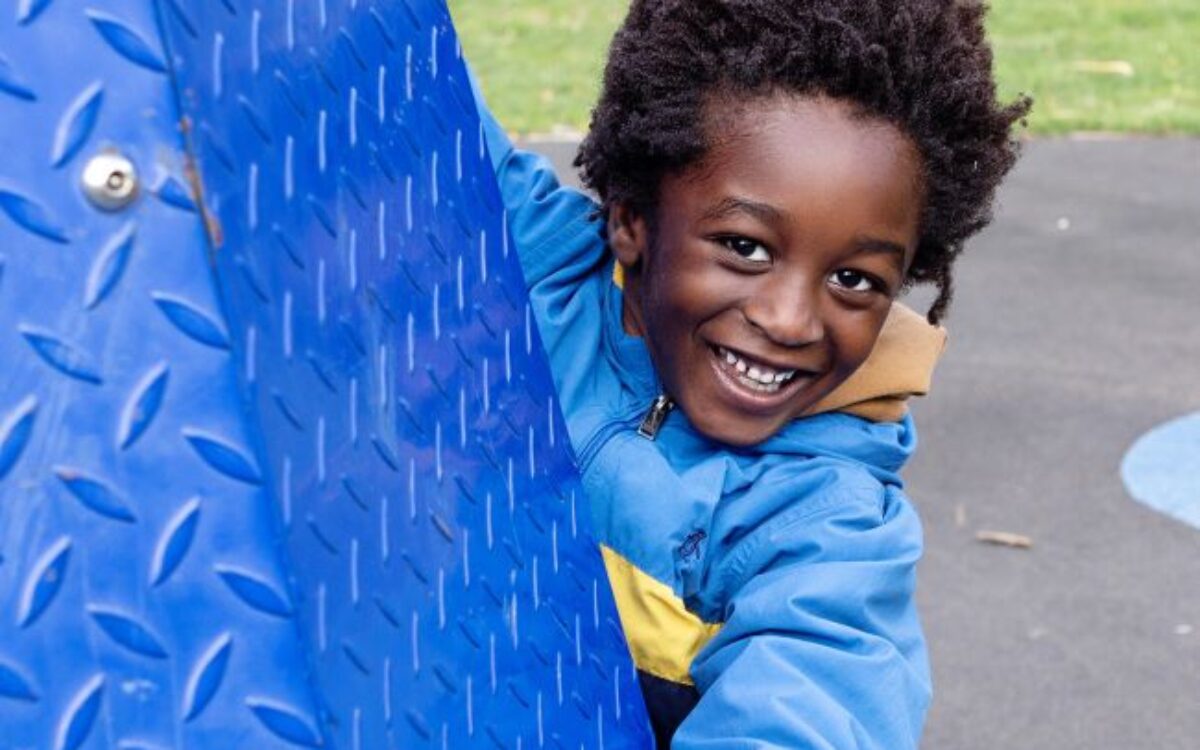 A young boy smiling on a climbing frame