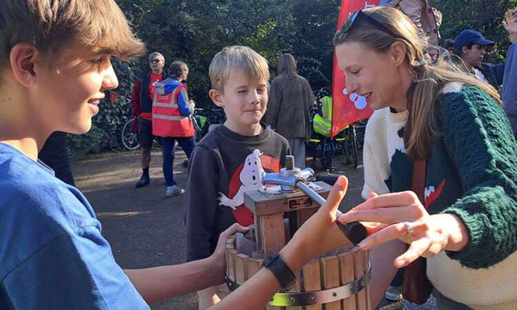 An adult and two children using an apple press