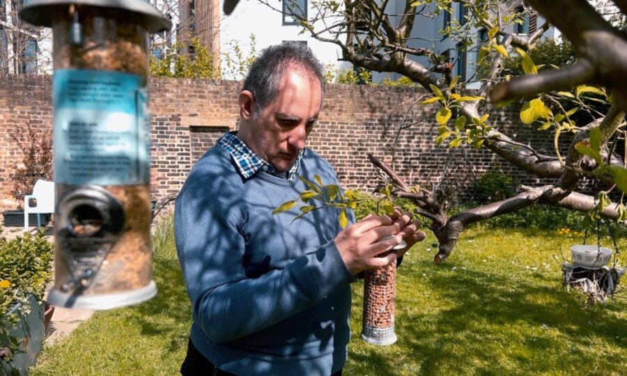 Person in a garden holding a bird feeder