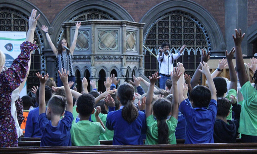 Students in Union Chapel with their hands in the air
