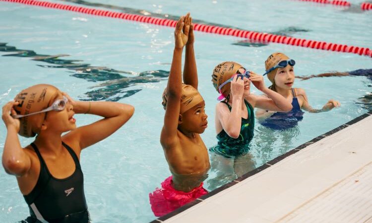 A group of children in a swimming pool taking part in swimming lessons