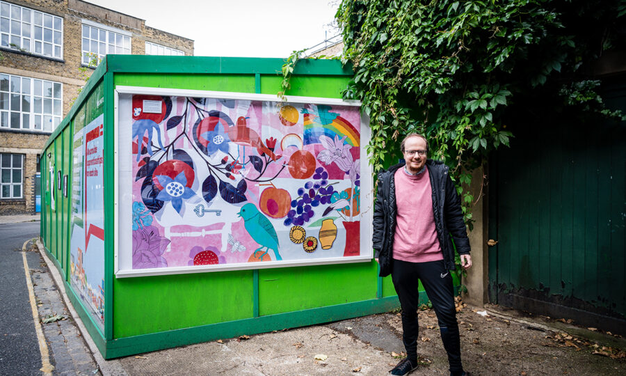 Artist Jack Haslam stood infront of his artwork on the hoardings in front of a new development on Windsor Street