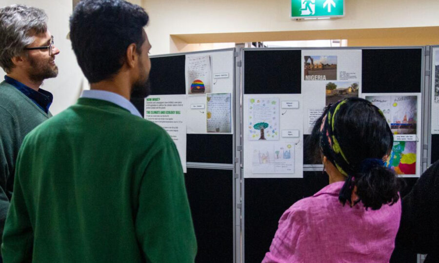 A man and a woman with their backs to the camera looking at a noticeboard of letters and images
