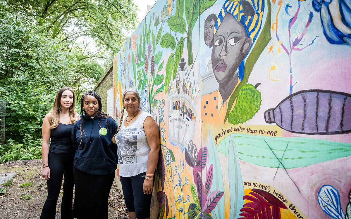 Council officer Isabella, youth cllr Tyra and resident Rani stood infront of the Windrush mural