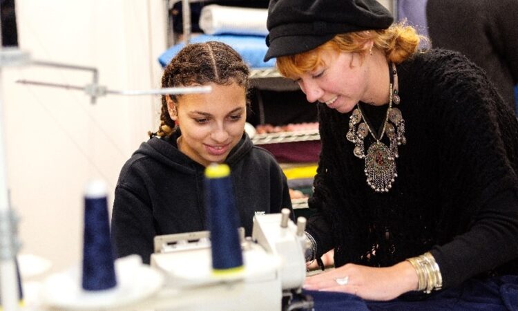 Woman helping young girl on a sewing machine