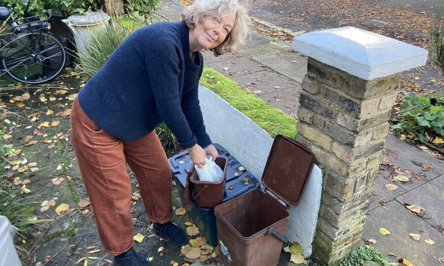 Recycling champion Caz Royds bent over putting something into her recycling bin in a garden