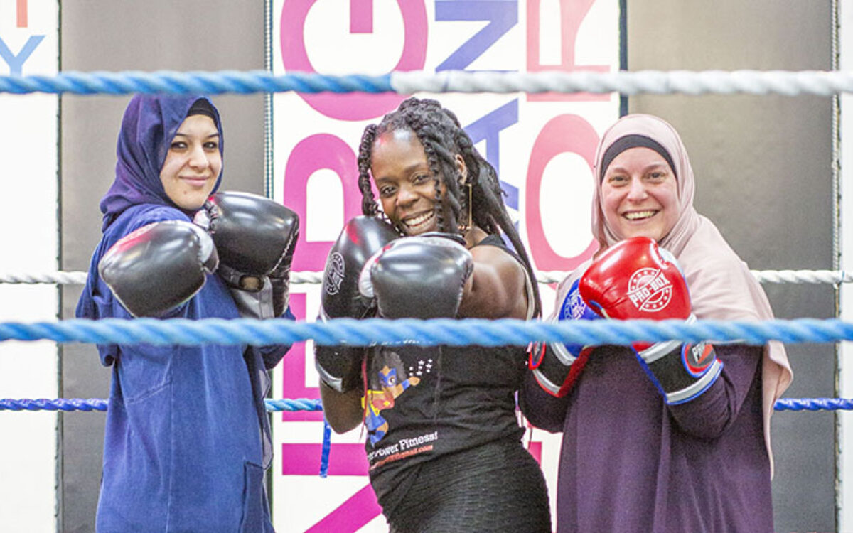 Three women in a boxing ring wearing boxing gloves at the Sobell Centre in Islington landscape