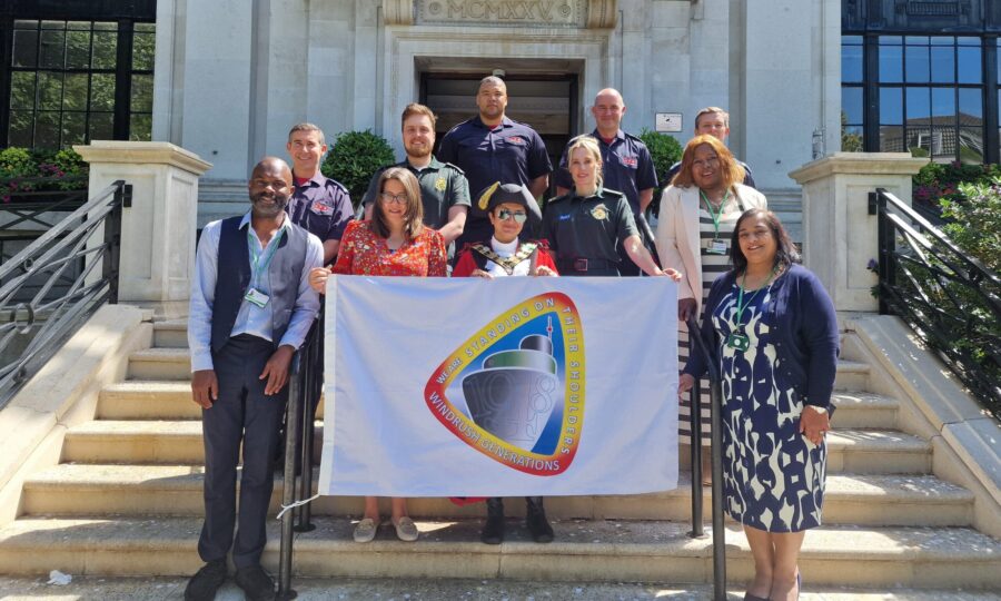 A group of people holding Windrush Flag on Islington Town Hall steps