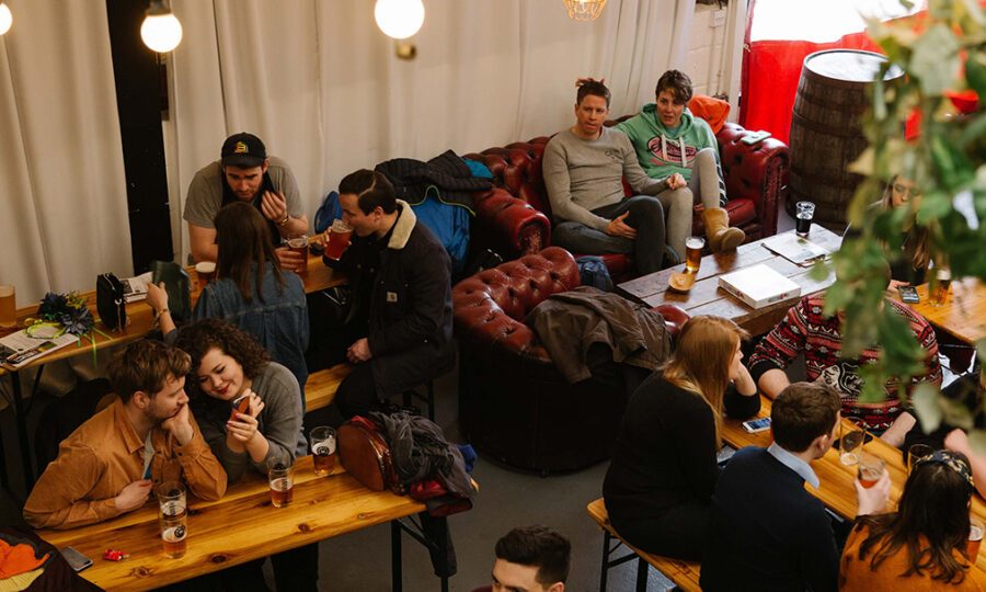 Aerial view of people sat on sofas and round tables drinking beer at Hammertown Brewery