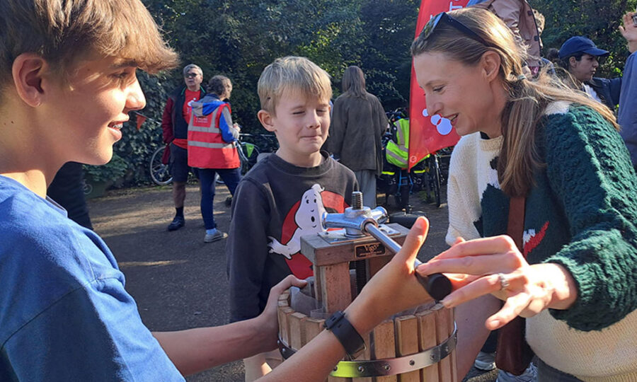 An adult and two children using an apple press