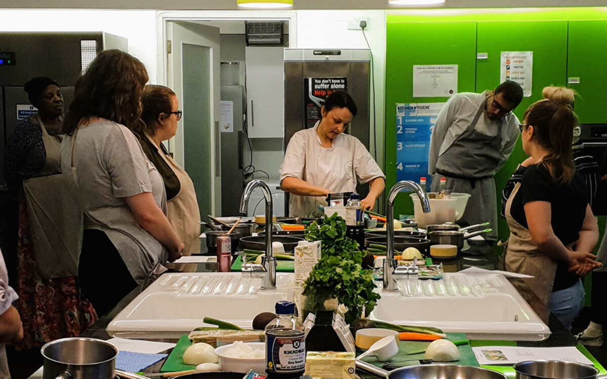 Chef at the head of a table of students teaching a cookery lesson