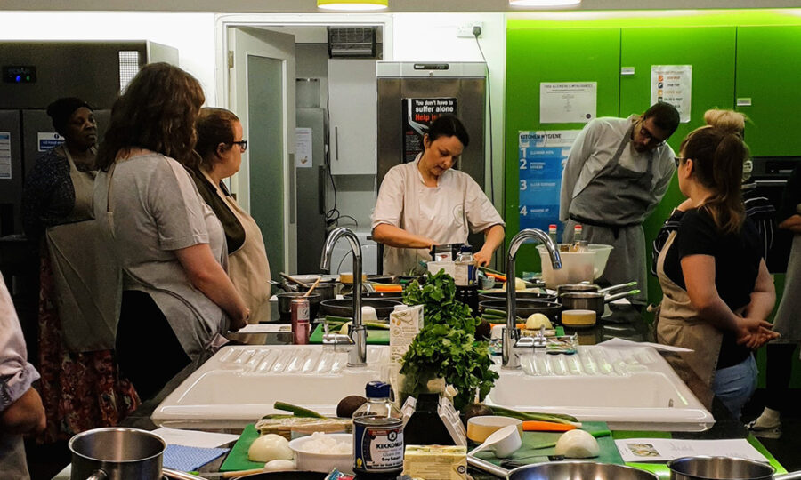 Chef at the head of a table of students teaching a cookery lesson
