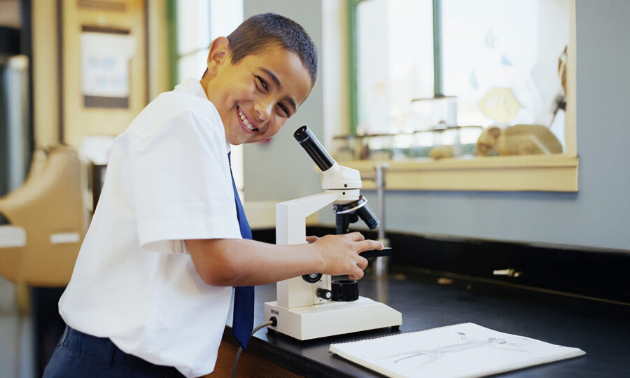 Young boy using a microscope smiling to camera