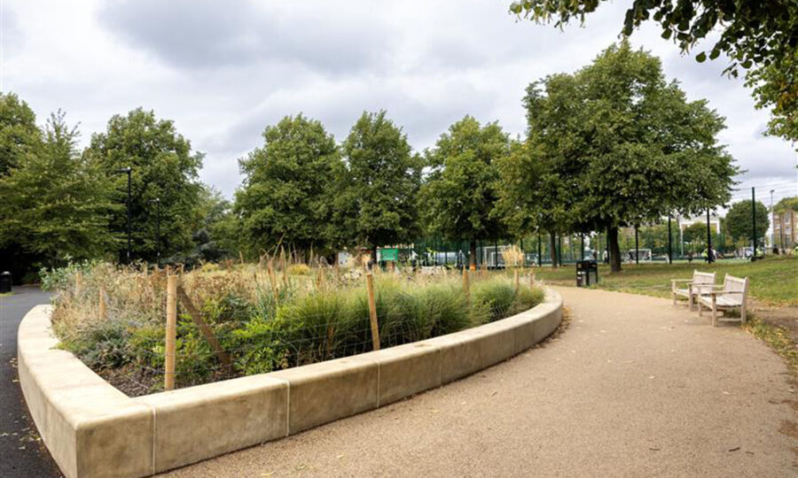 A sweeping path with a flower bed, lined with trees