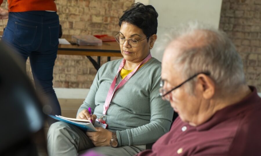 An older lady with short black hair wearing looks down at a piece of paper