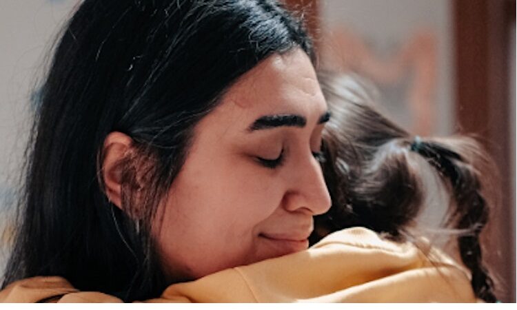 Woman with black hair hugging child