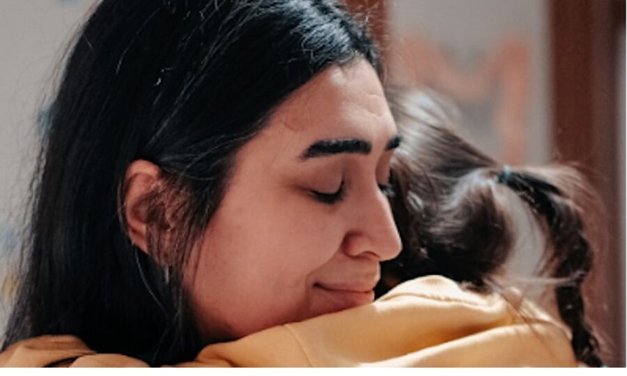 Woman with black hair hugging child