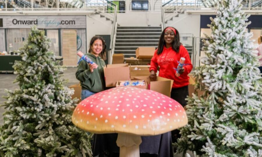 Two women holding Christmas crackers with a festive backdrop