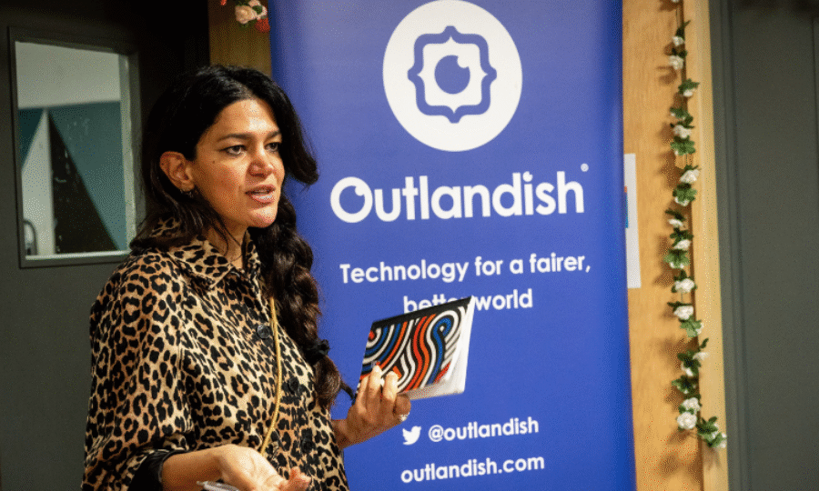 A woman wearing a leopard print shirt and hair in a plait giving a speech