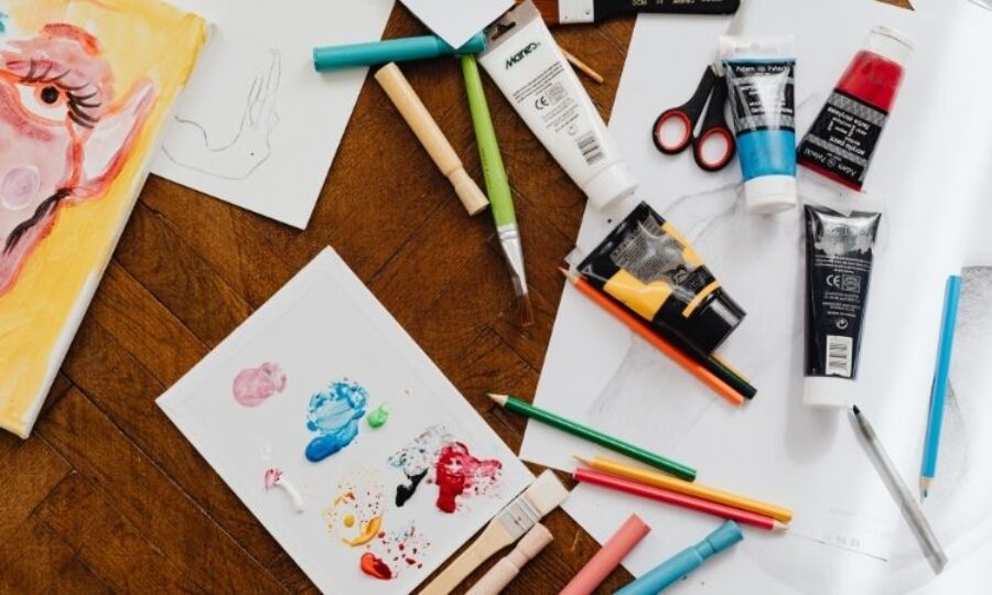 Paper, colouring pencils and paints laid out on a table