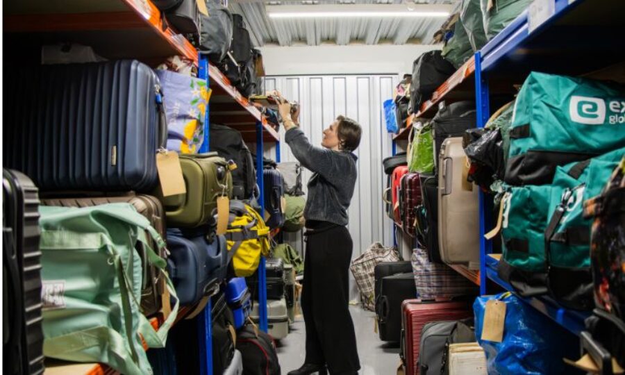 Woman pulling out a suitcase in a storage room full of other bags
