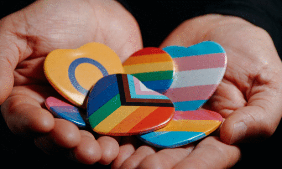 Person holding different LGBTQ+ pins in their open palms