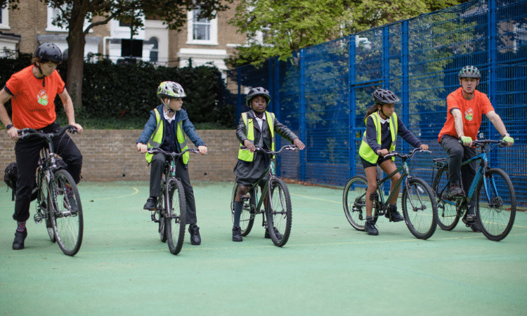 Children riding bikes with instructors on each side