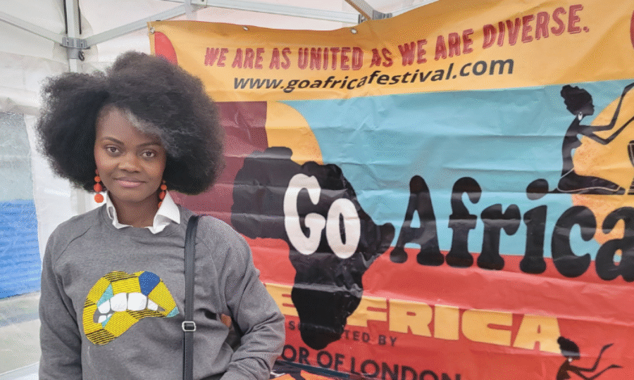 A woman smiling at the camera with a 'Go Africa' sign behind her