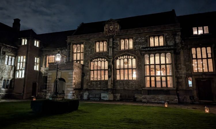 Dark grand building at night time with light streaming through several windows