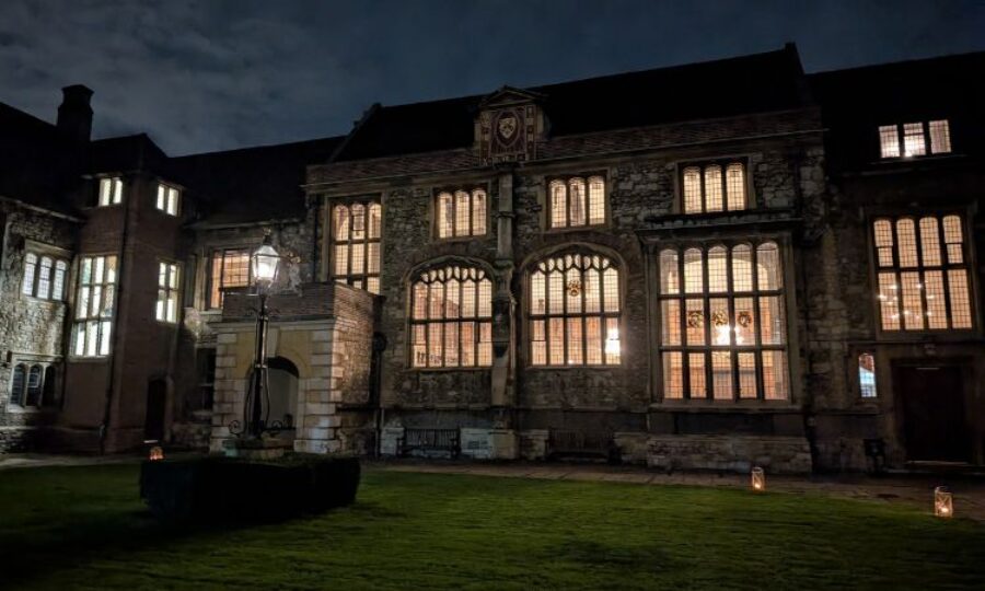 Dark grand building at night time with light streaming through several windows