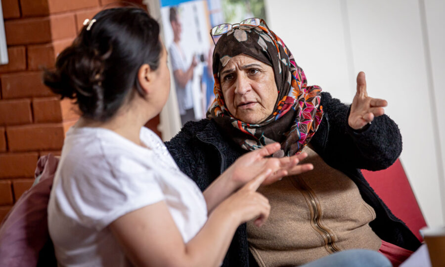 Two women talking to one another. One is wearing a hijab