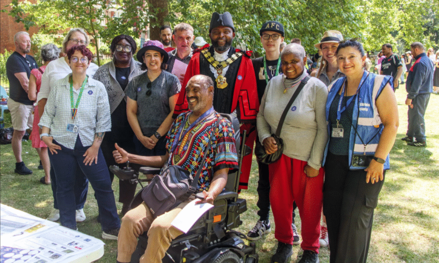 A diverse group of people standing outside in a park smiling including the Mayor of Islington and man in a wheelchair