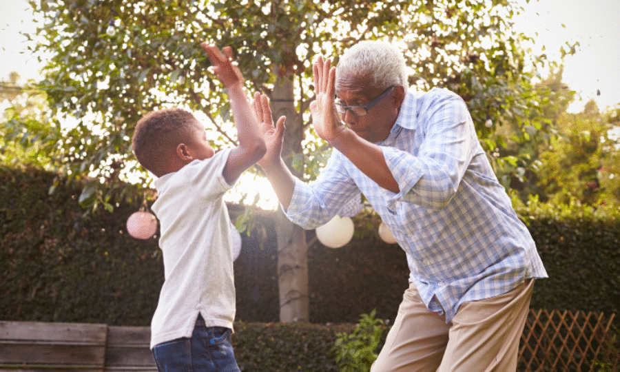 Black Grandfather Playing With His Grandson In A Garden